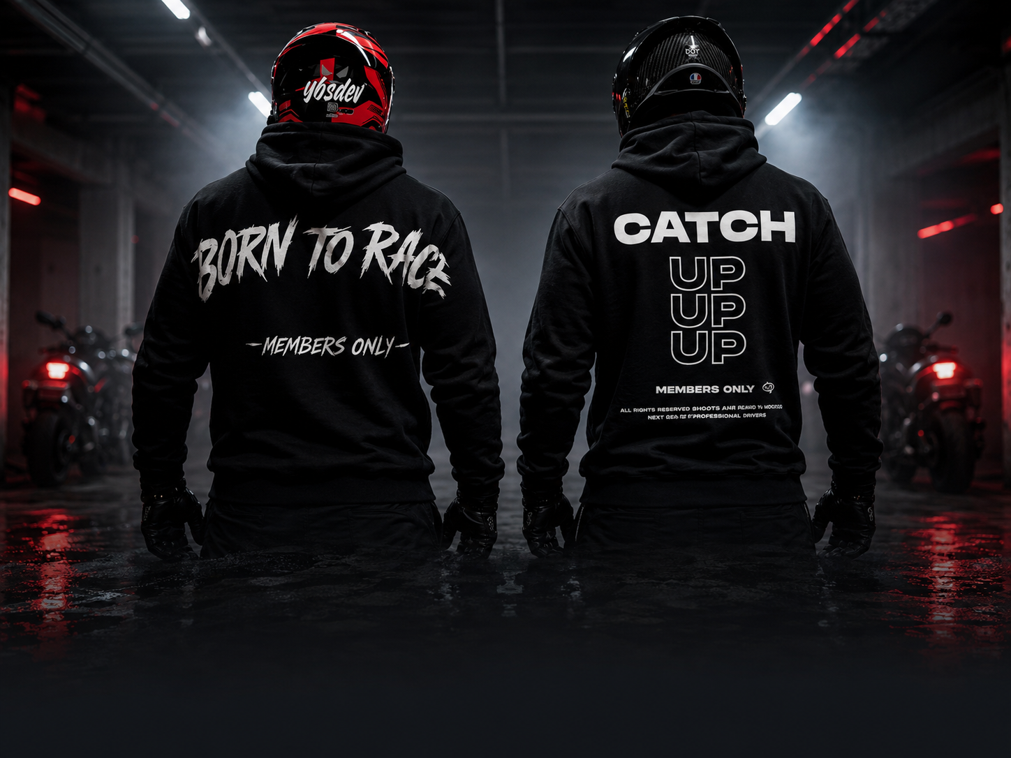 Two helmeted riders wearing the black Born To Race and Catch Up reflective hoodies in an after-hours garage